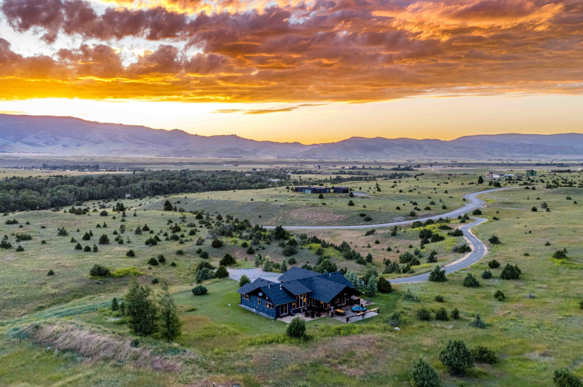 aerial view of Mountain Sanctuary, one of our Montana Luxury Vacation Rentals. the property is located in the foreground, with the mountains and a beautiful sunset in the background.